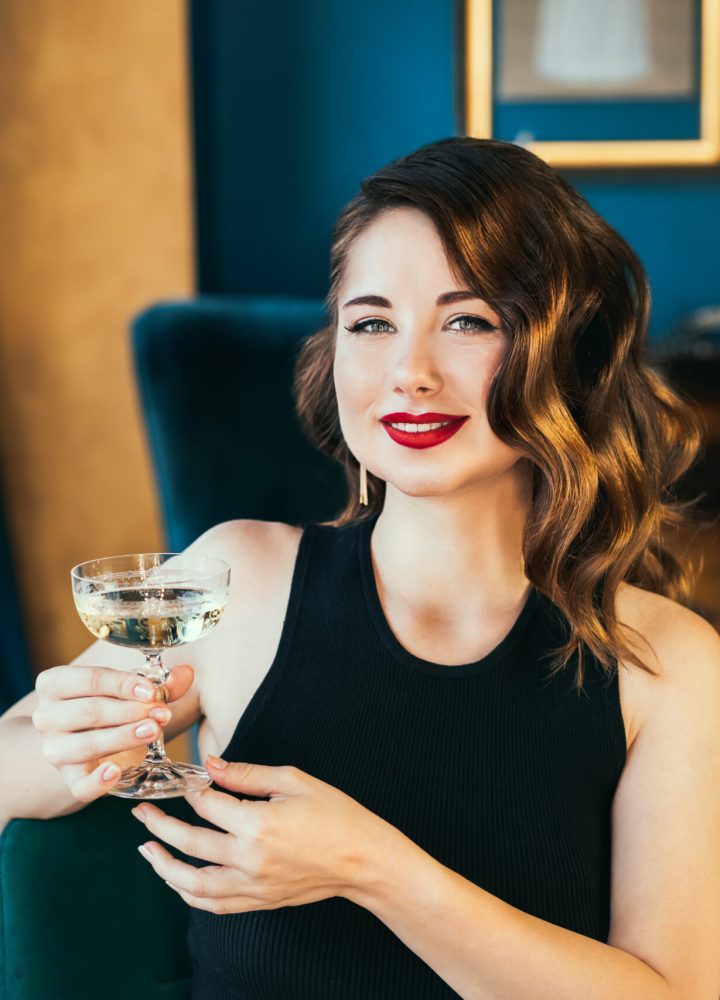 Portrait of posh elegant woman in evening dress with a glass of champagne in the luxury interior. Celebrity, superstar lifestyle. Party, drinks, holidays and celebration concept. Selective focus.